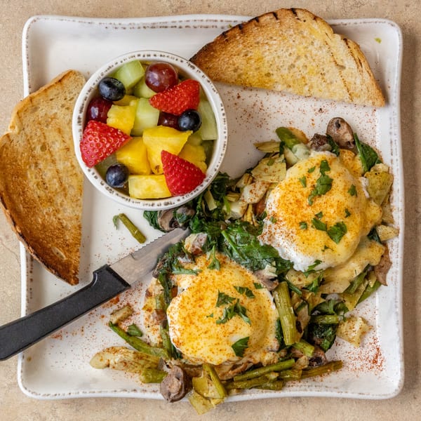 Chicken Run's breakfast plate with poached eggs, sautéed vegetables, fruit salad, and toast.