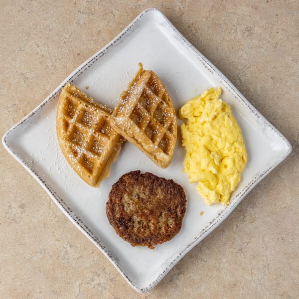Chicken Run's breakfast plate with two waffles, scrambled eggs, and a sausage patty.