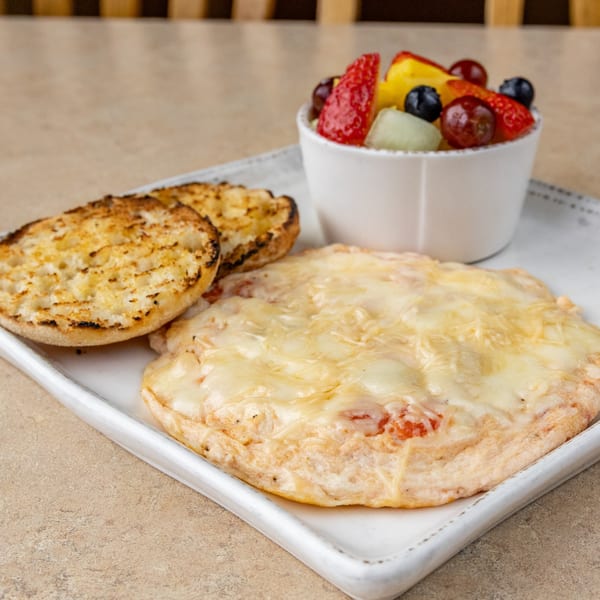 A breakfast plate with a cheesy omelet, toasted English muffin, and a side of fresh fruit.